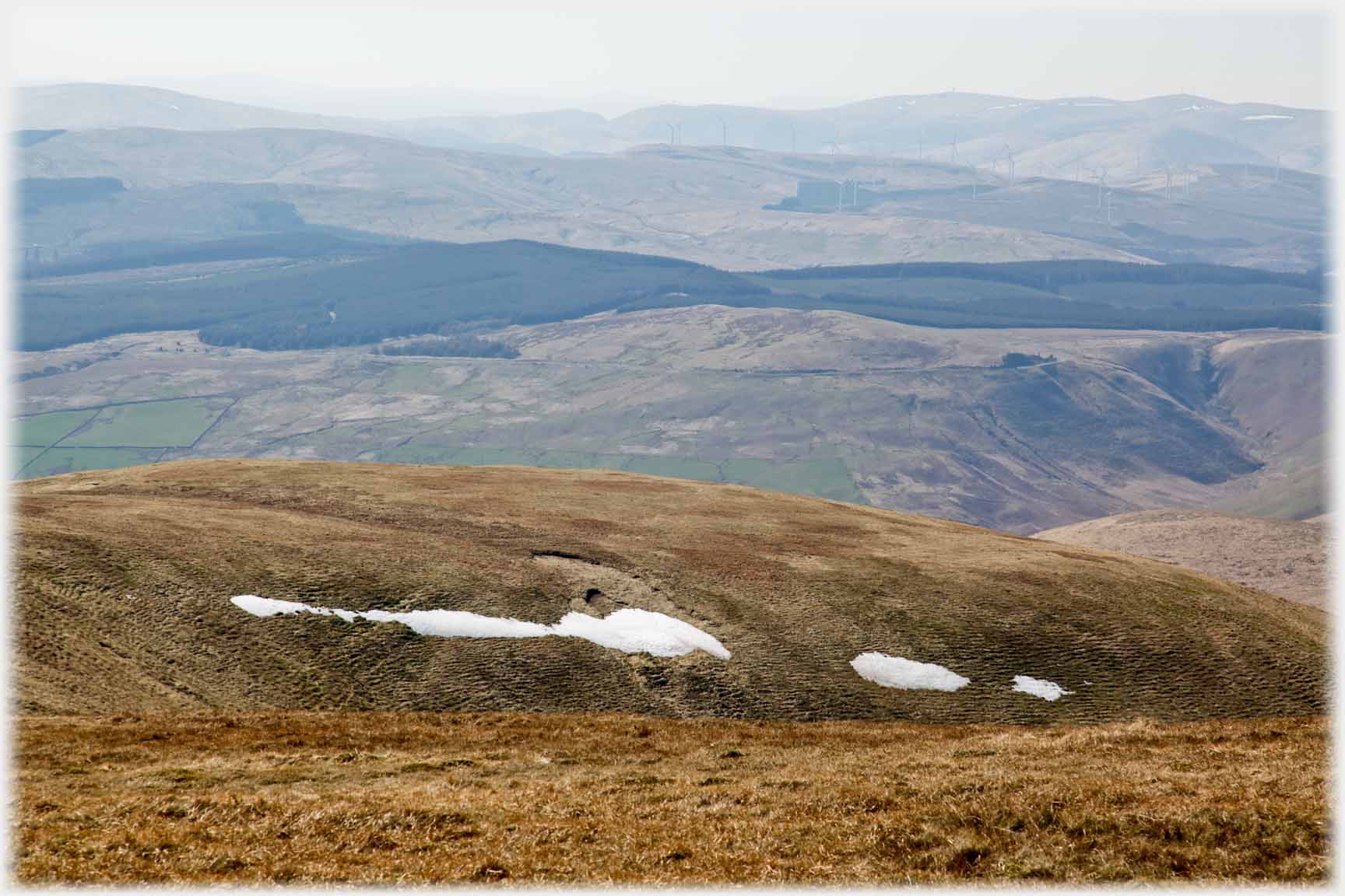 Looking out across hills, in foreground very small patches of snow.