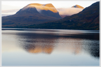 Morning mist clearing from hills reflected in loch.