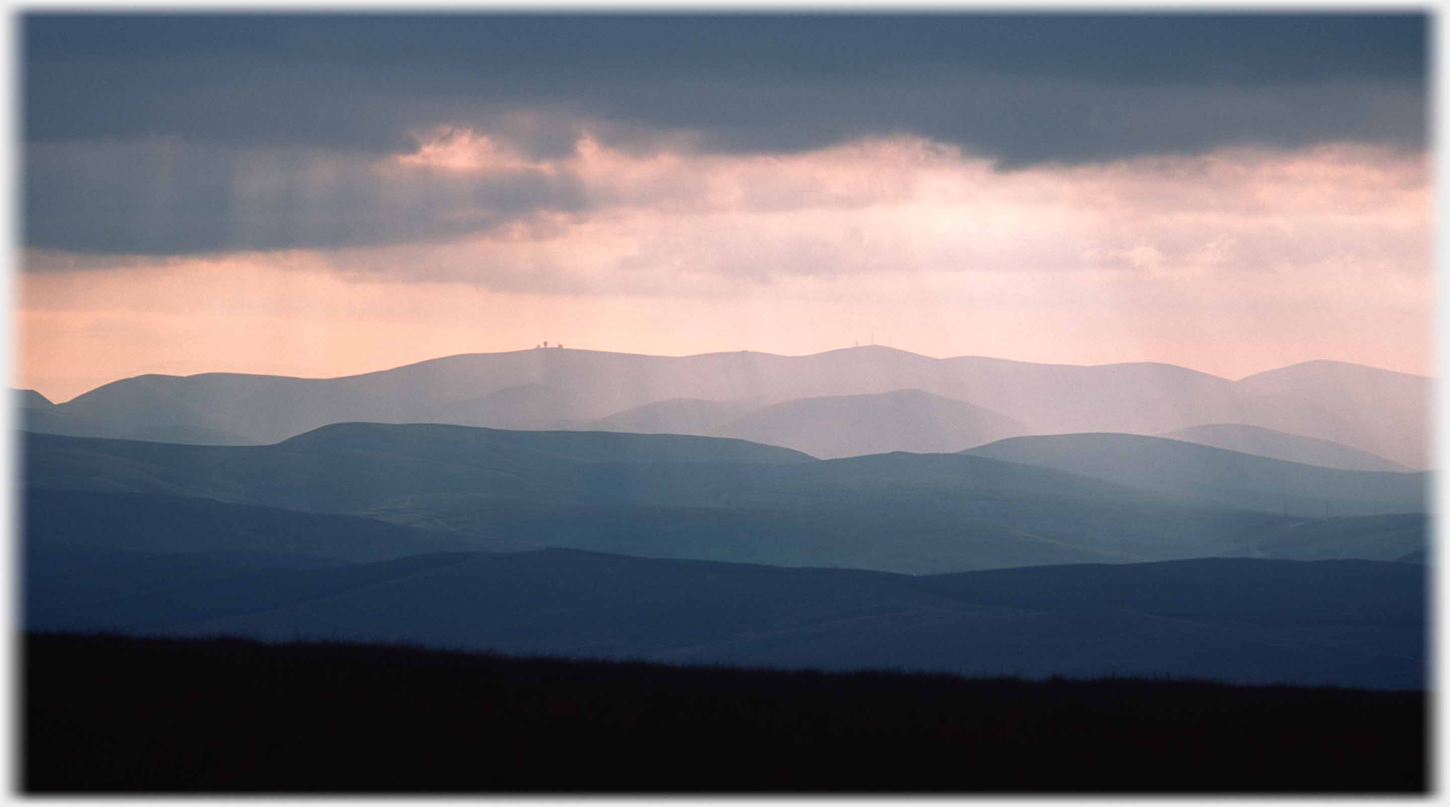 Waves of hills in evening light with construction on far hill.