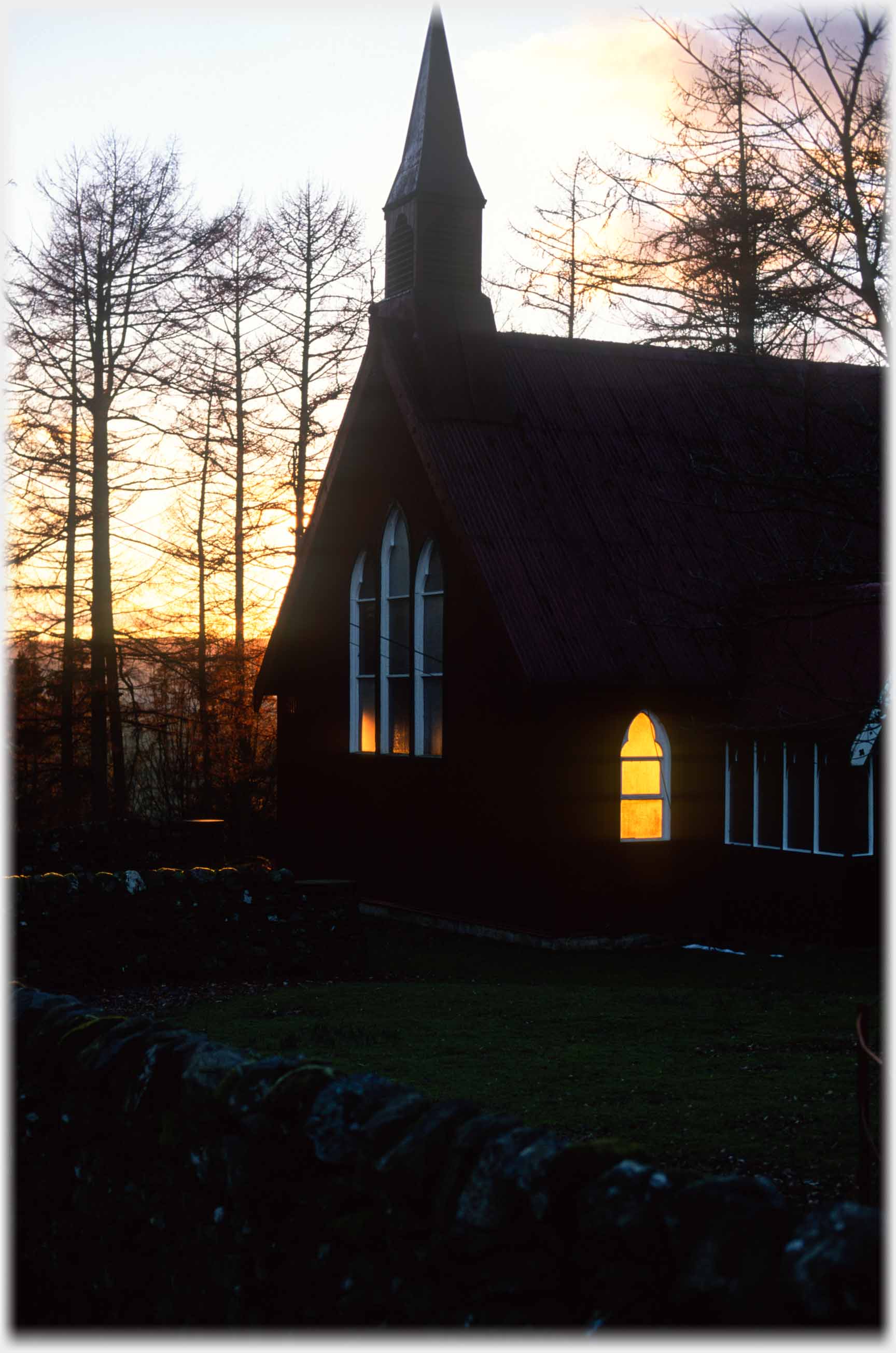 Chapel with setting sun behind it showing through one window.