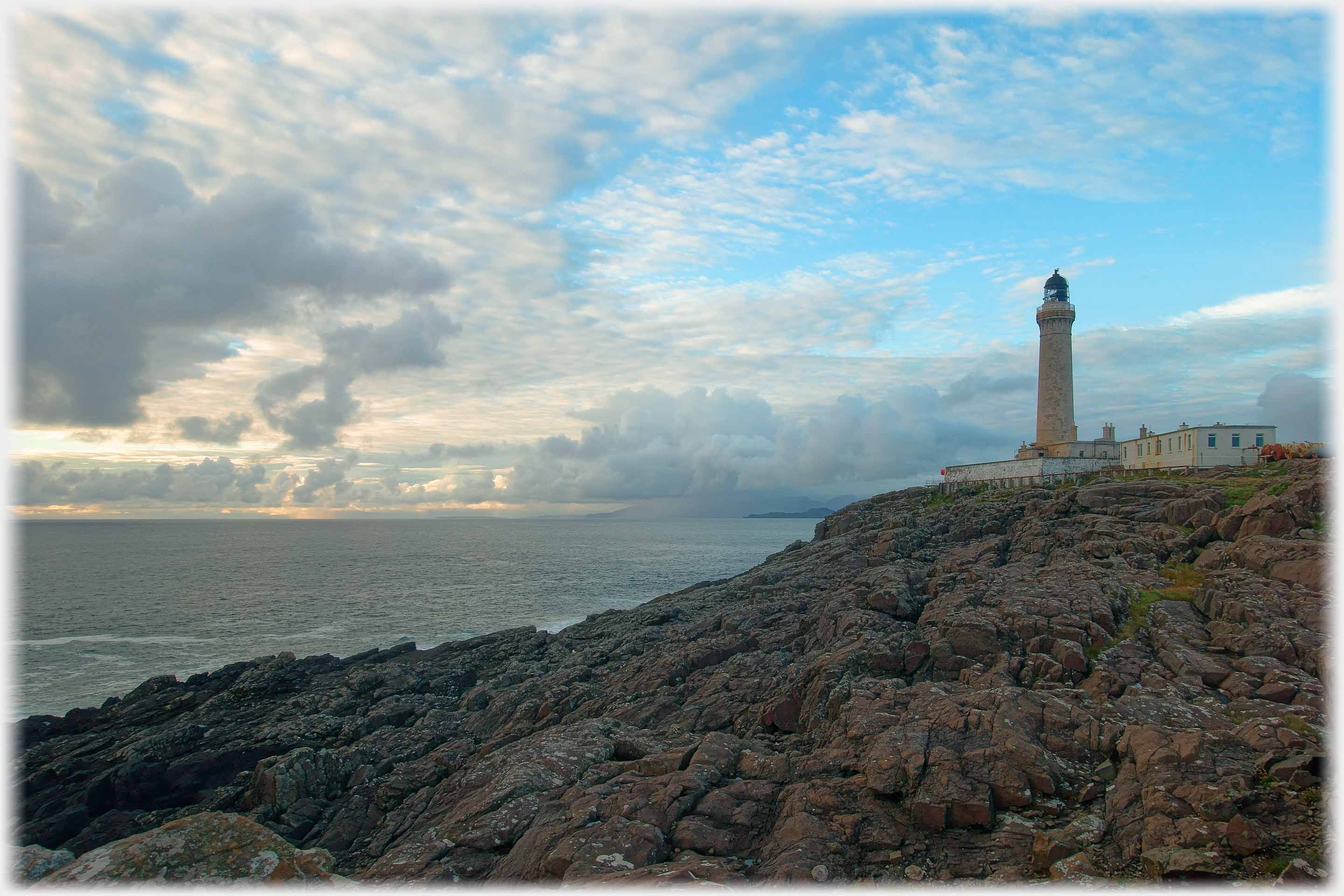 Lighthouse on rocks looking over sea.