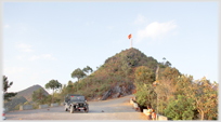 Small hill with flag on top, Jeep in foreground.