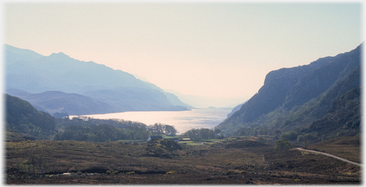 Steep hillsides running into loch, against sunlight.