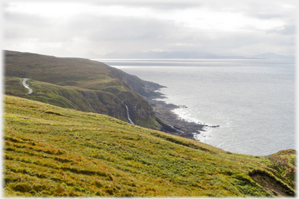 Cliffs with thin line of waterfall, land on the horizon.