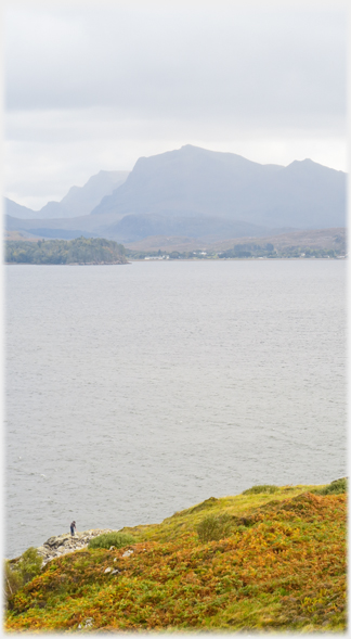 Loch with figure and steep hills on far shore.