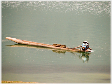 Woman putting fish trap into lake.