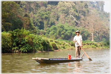 Boat and man against the rich jungle background.