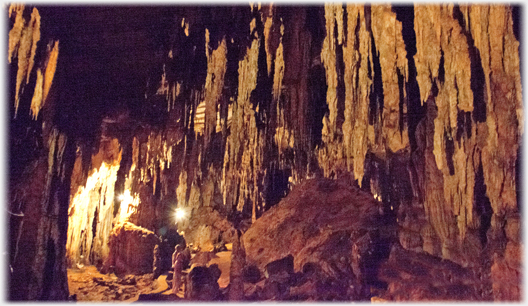 People in large cave with many stalactites.