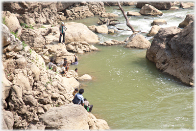 People fishing by river.