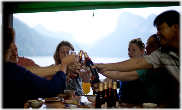 Group drinking beer with hills in background.