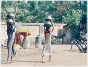 Two girls with larege pots on their heads.
