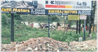 Rubble dump, hoarding and tented area.