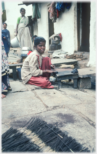 Woman making joss sticks at table.