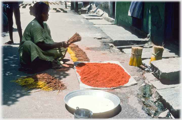 Woman making joss sticks on the ground.