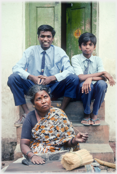 Boys at door, woman making joss sticks.