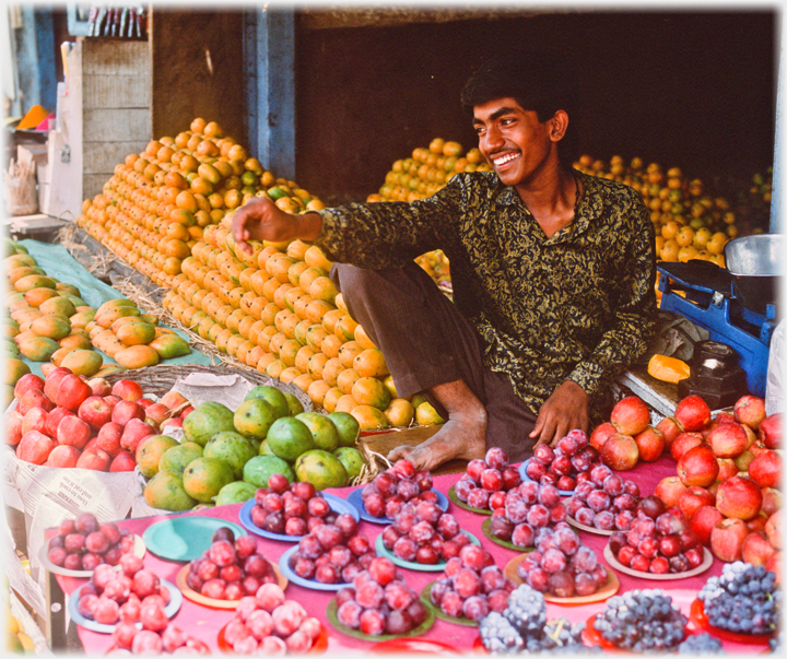 Man crouching amongst his fruit display.