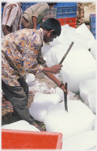 Man cutting up large pieces of ice