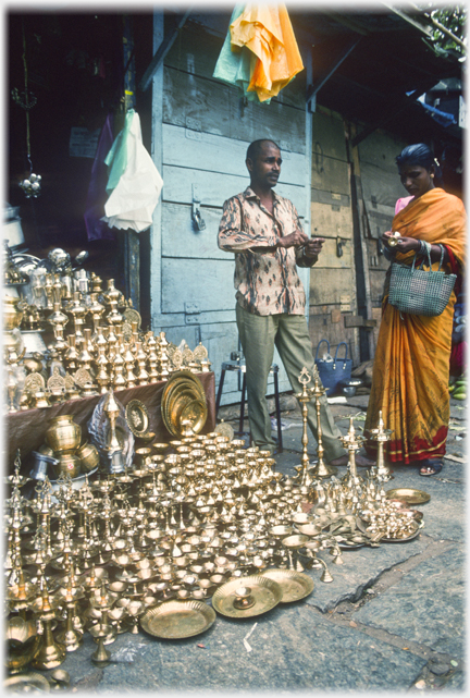 Small shop with great quantity of shinning brass objects displayed outside.