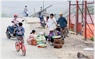 Woman selling at roadside by bridge.