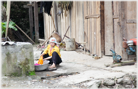 Woman washing clothes by well.