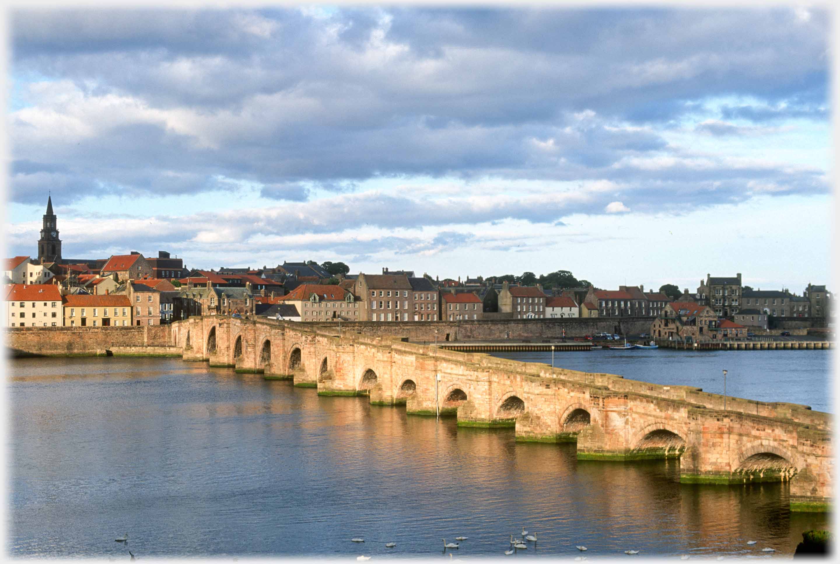 Berwick town with the old bridge running to it caught in the evening sun.