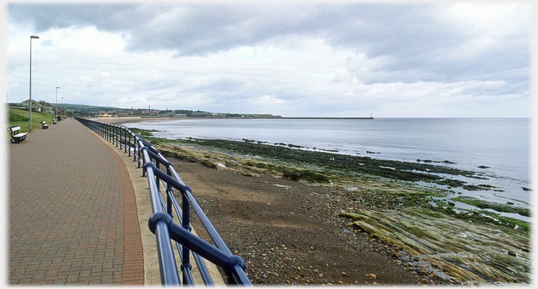 Promanade railings, rocky shore and pier lighthouse.