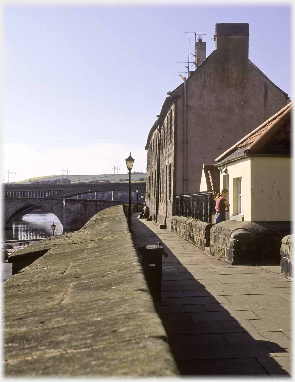 Parapit of wall running towards bridges, row of houses to right.