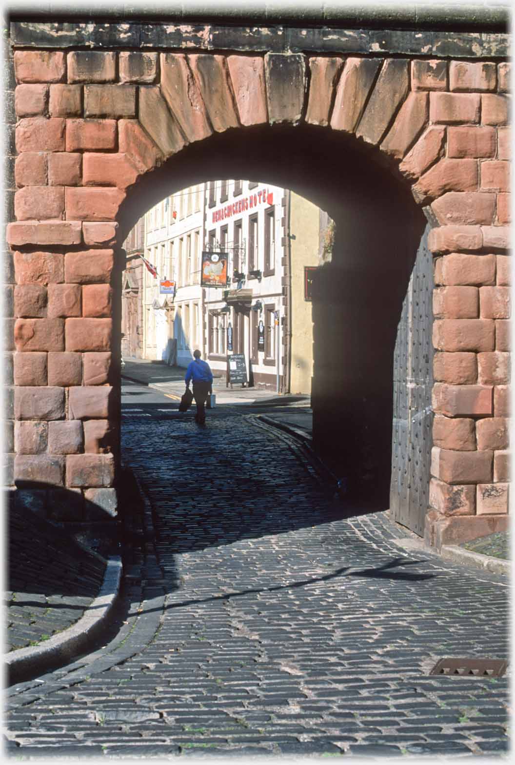 Road through wall with hotel ahead.