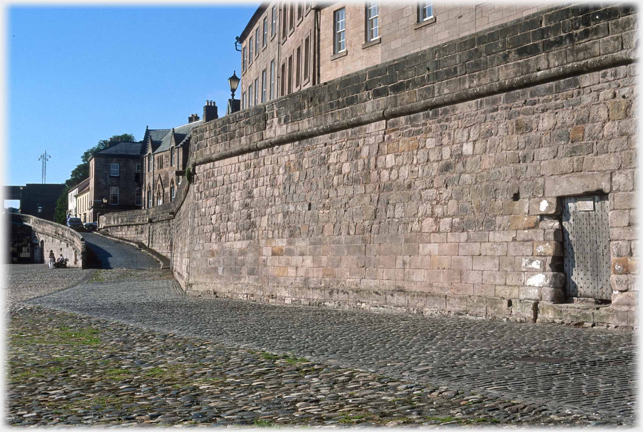 Wall leading to ramp onto bridge, door at right in wall.