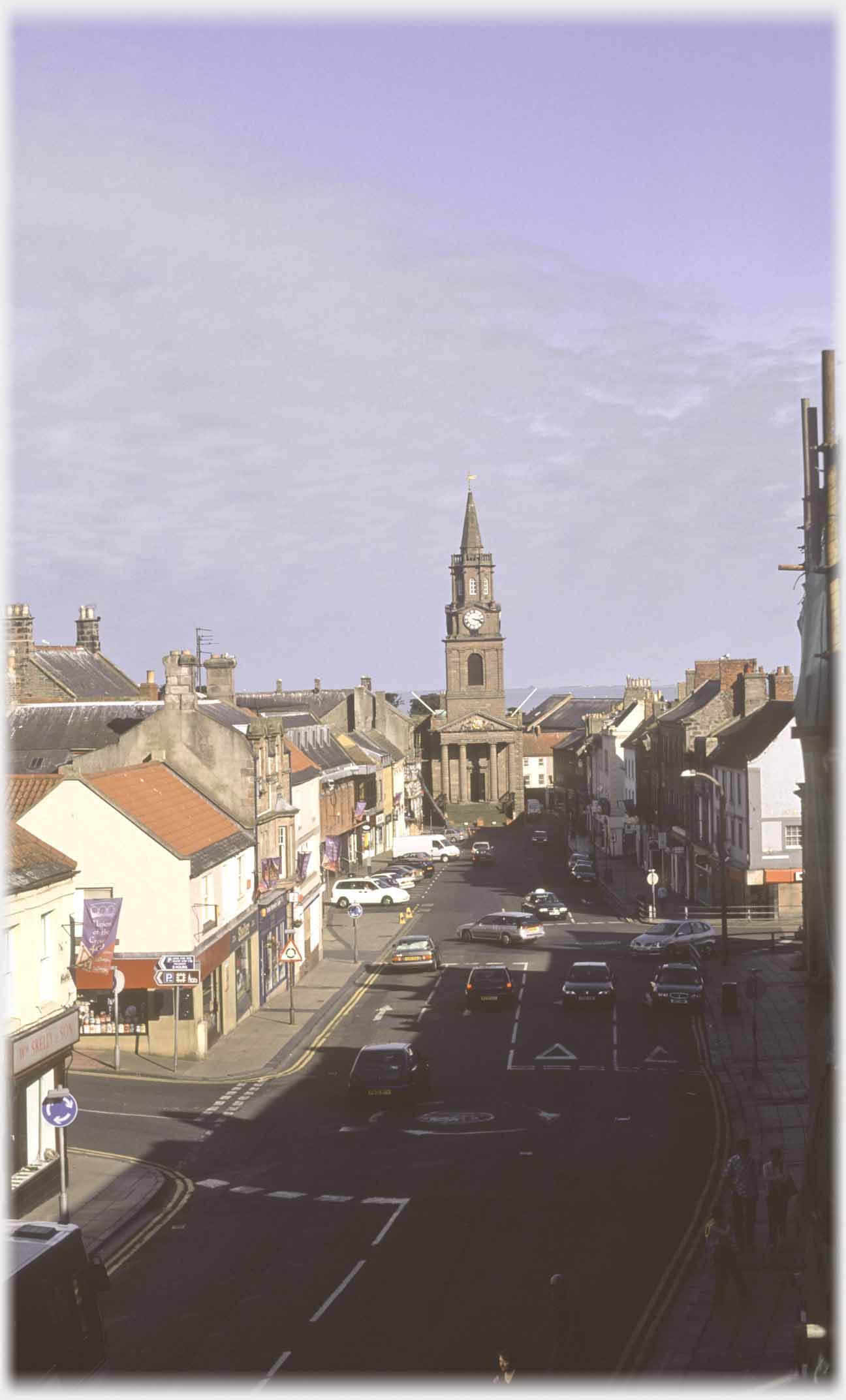 Looking down at main street with spired building at end.