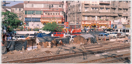 Clutter of stalls an cars by the railway.