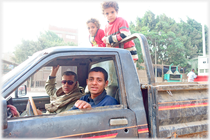 Men and kids in small truck.