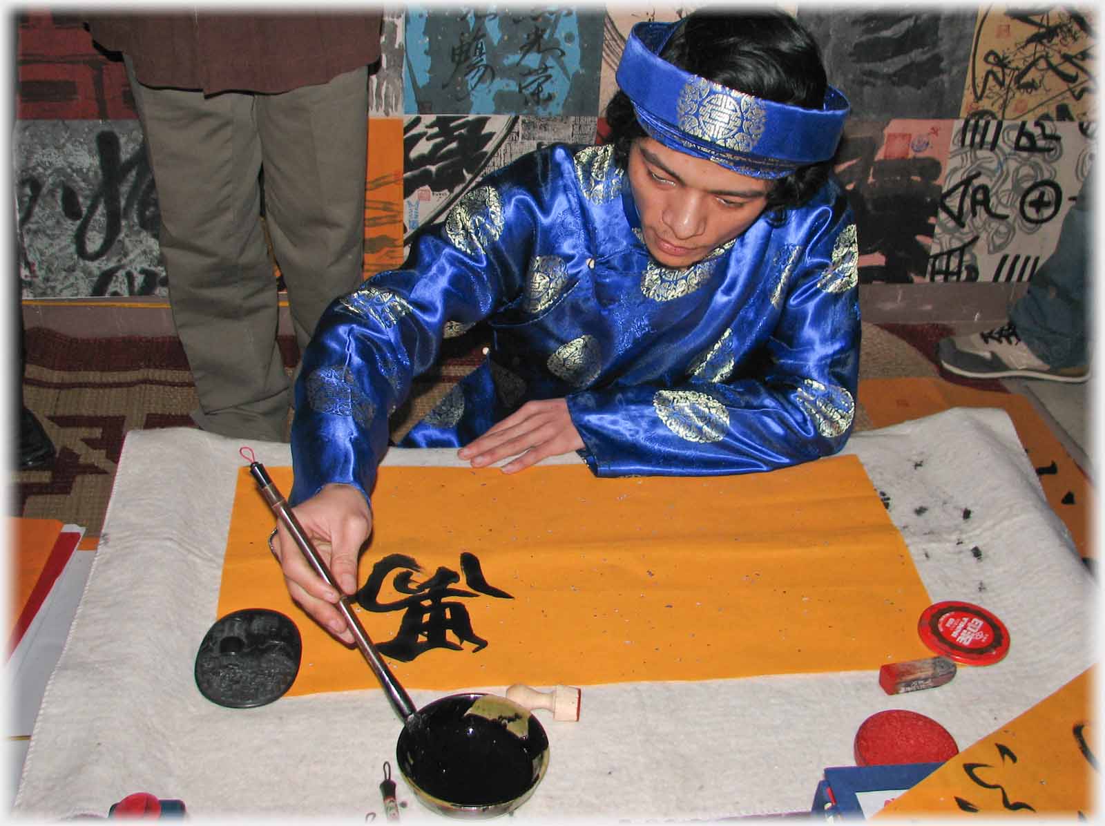 Man in blue dipping his pen.