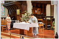 Woman in kimono writing with brush in church.