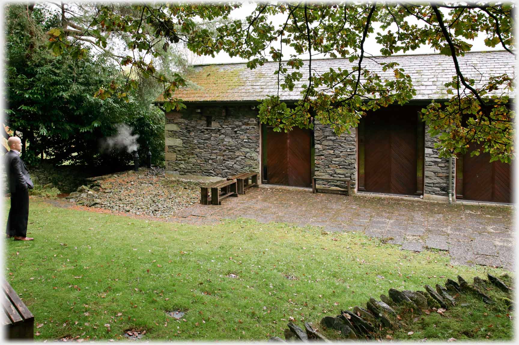 Stone building with wooden panels, man standing.