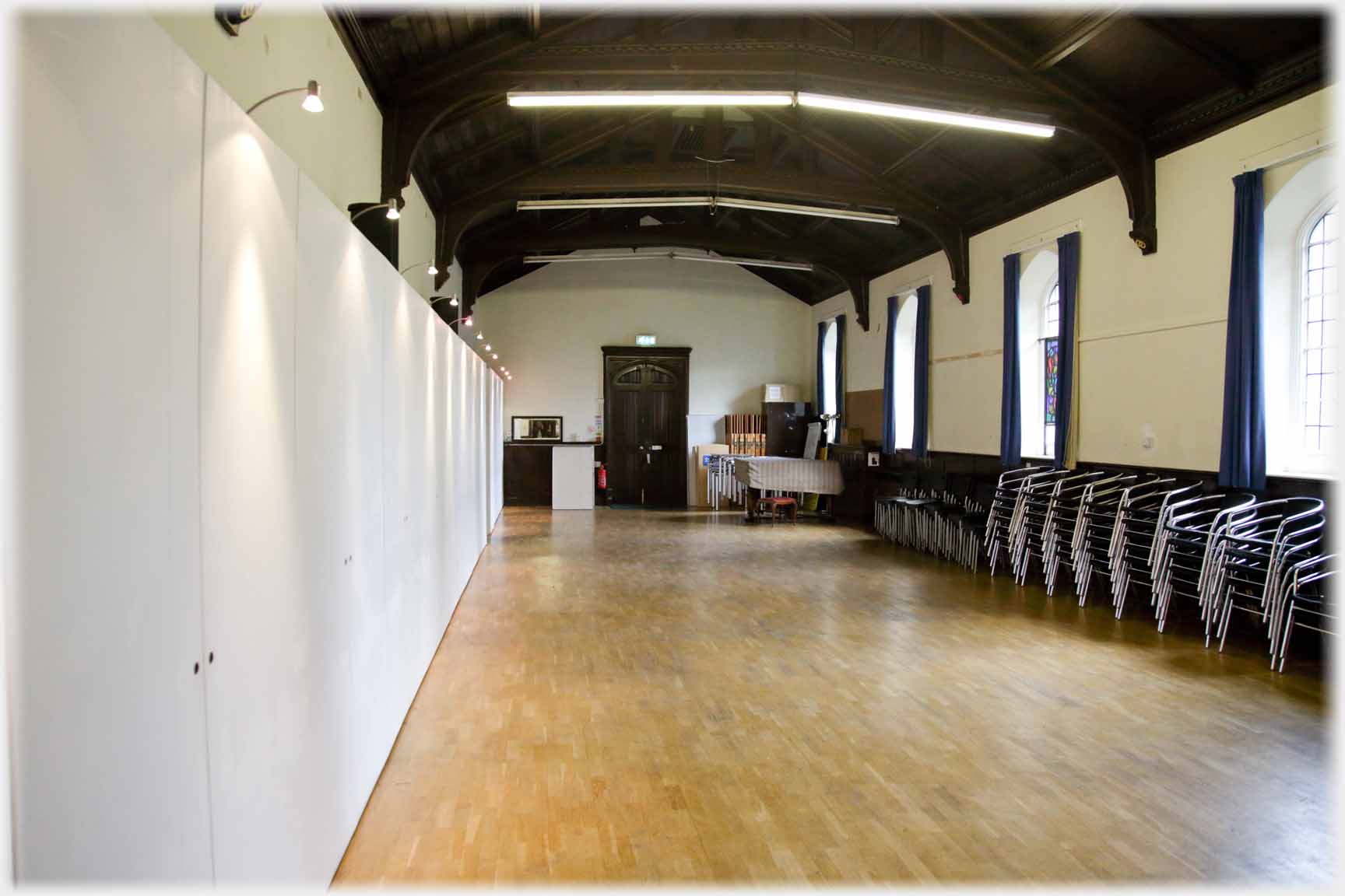 Empty room with white wall and stacked chairs.