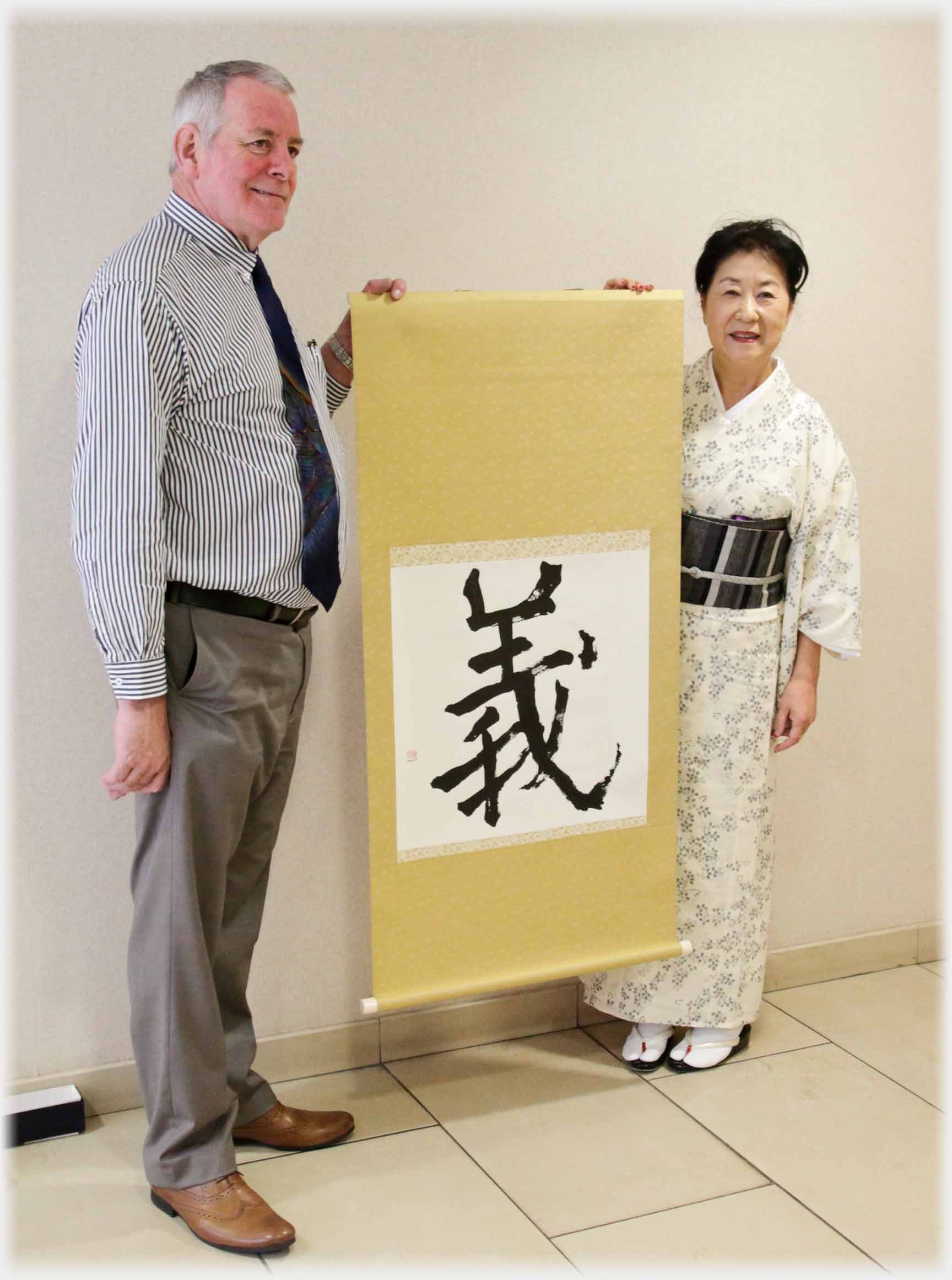 Man and woman in kimono, holding up mounted character.