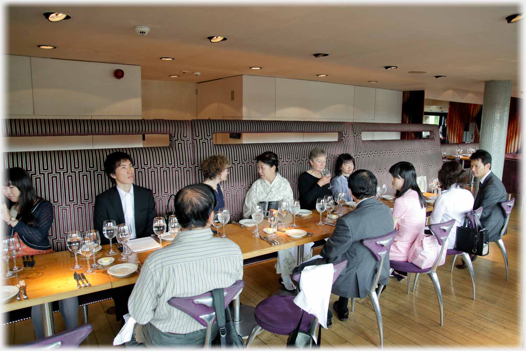 Long table with places set, and people down either side.