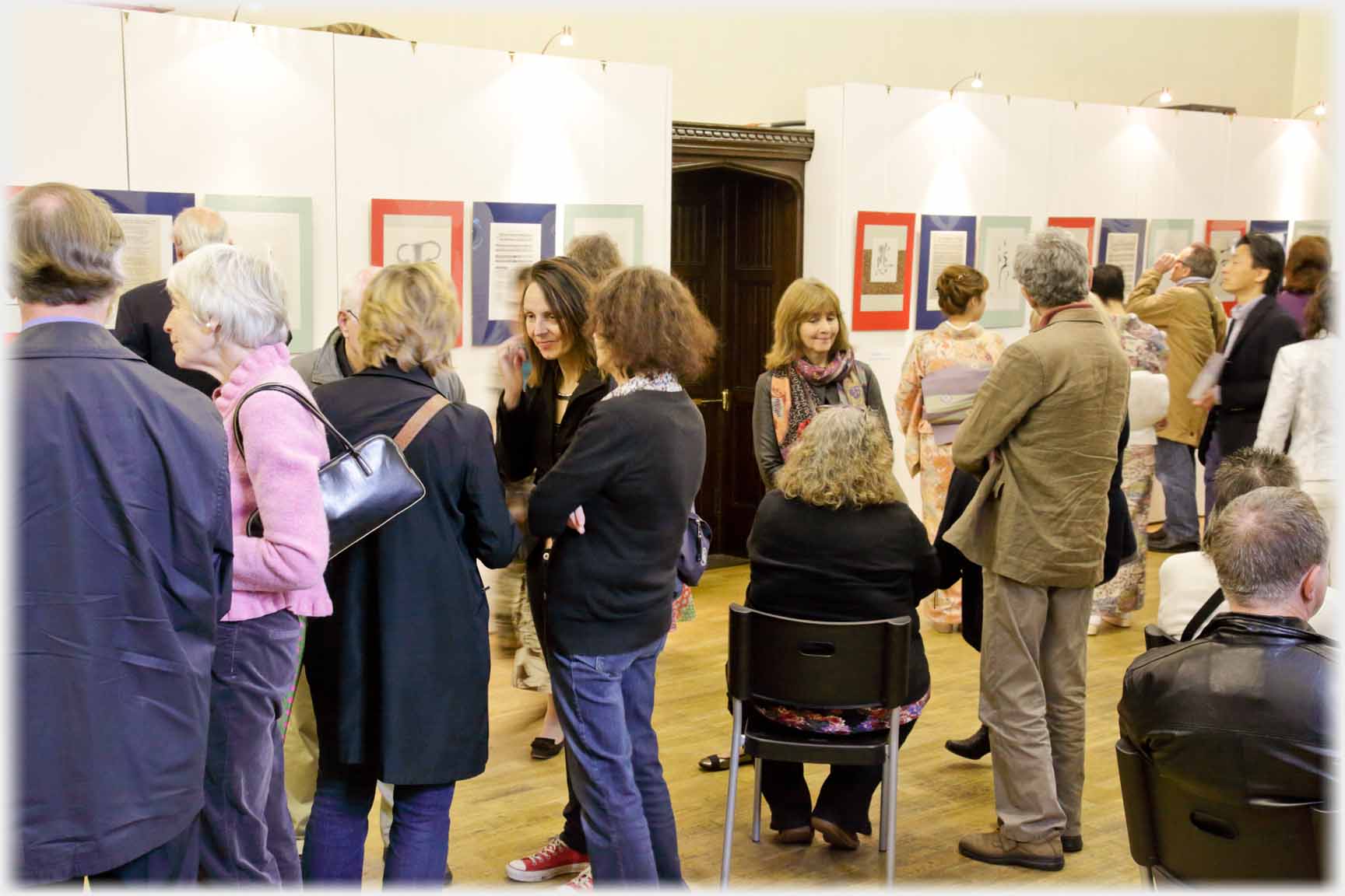 Room busy with people, exhibits in background.