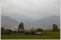 Stone cirlce, valley and clouded hills beyond.