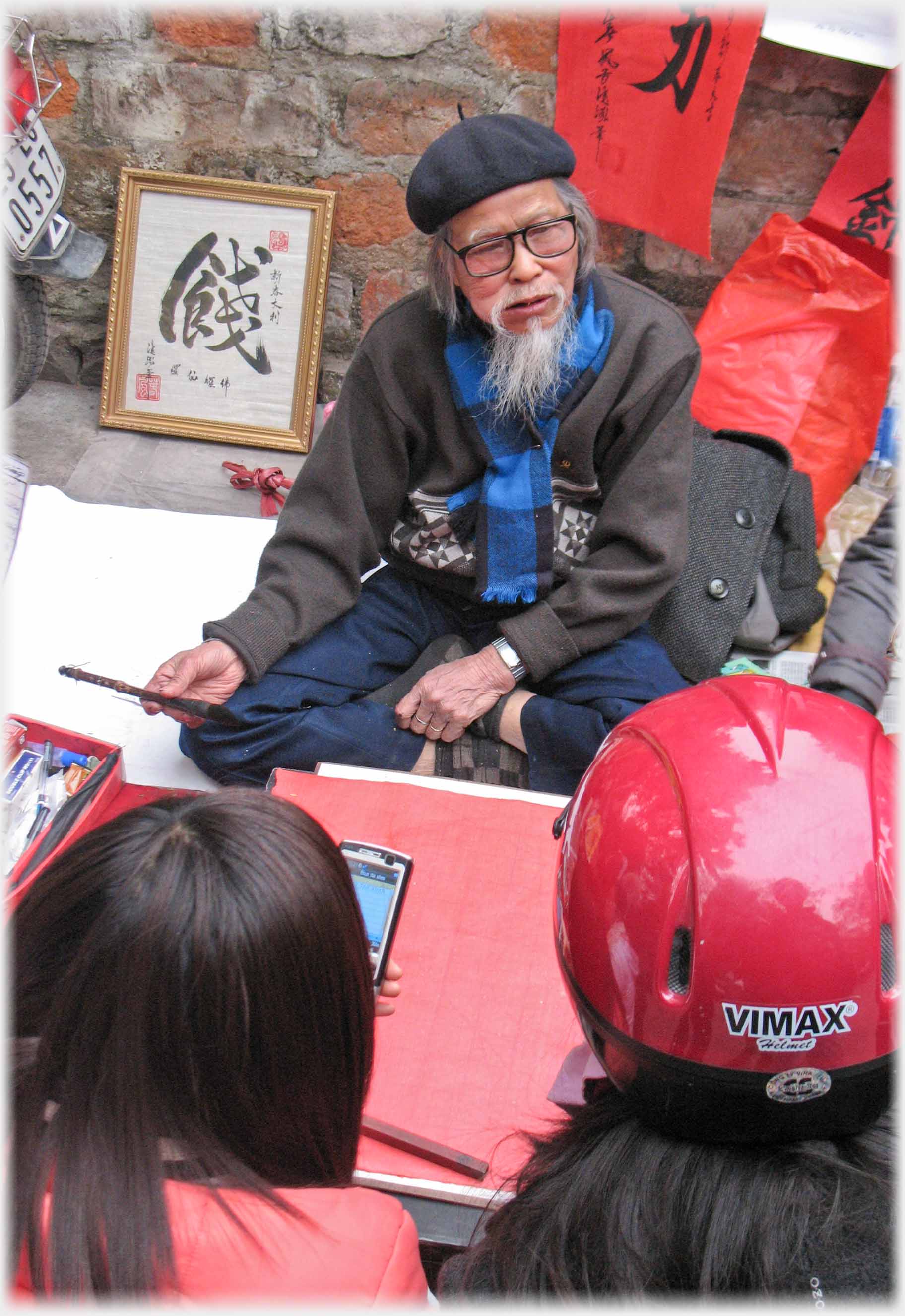 Man in Beret with white beard and glasses looking up at helmeted person.