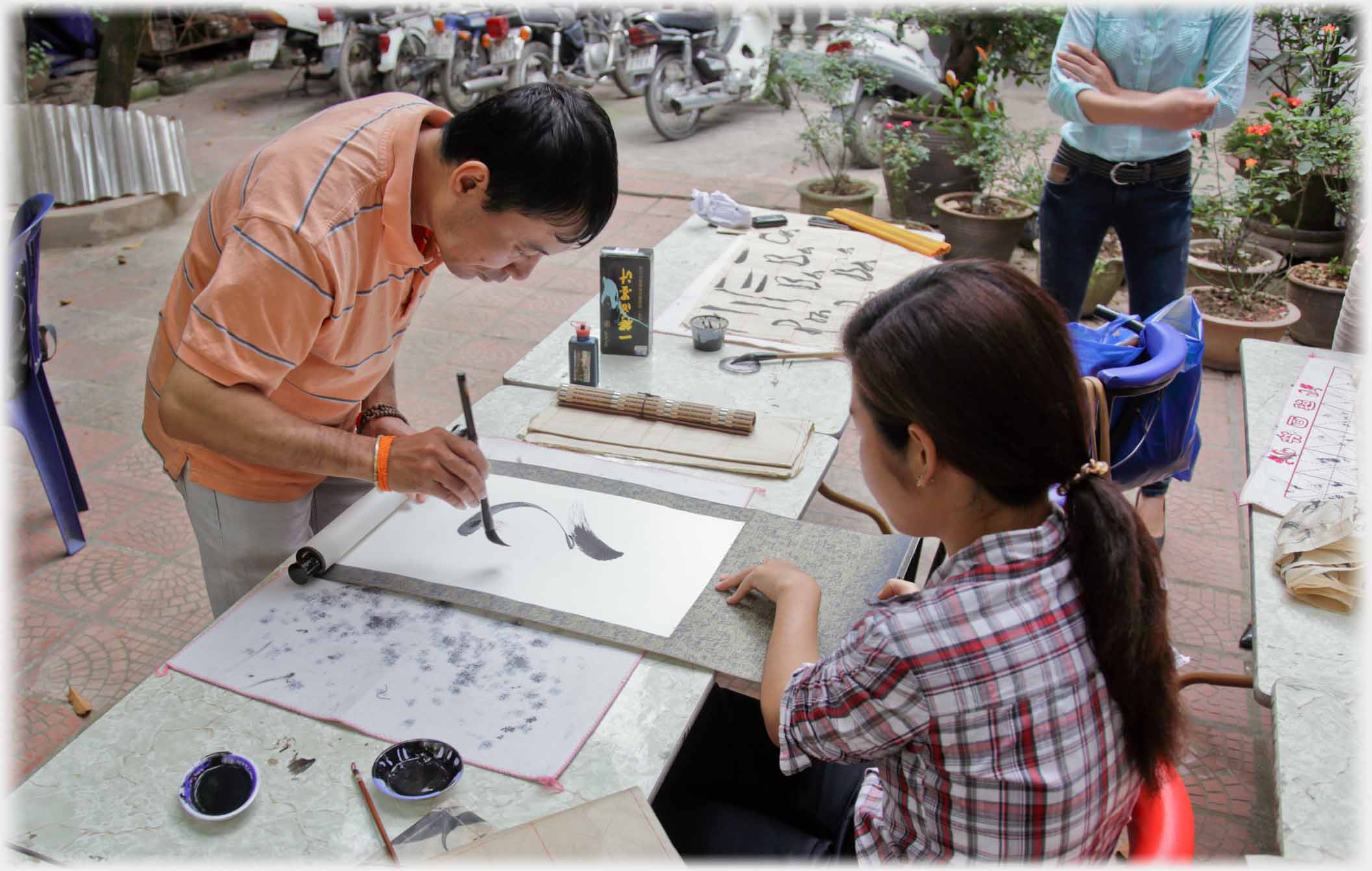 Teacher writing large letter, pupil holding paper.