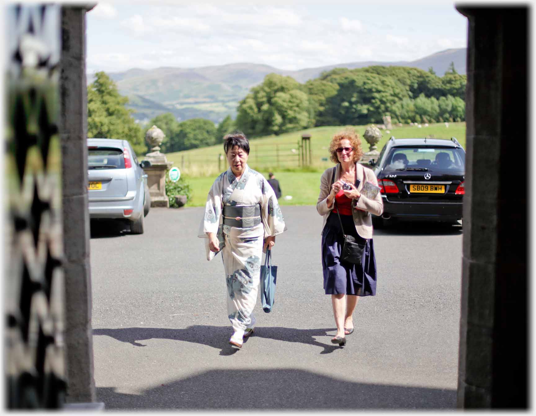 Two women walking towards door one in kimono.