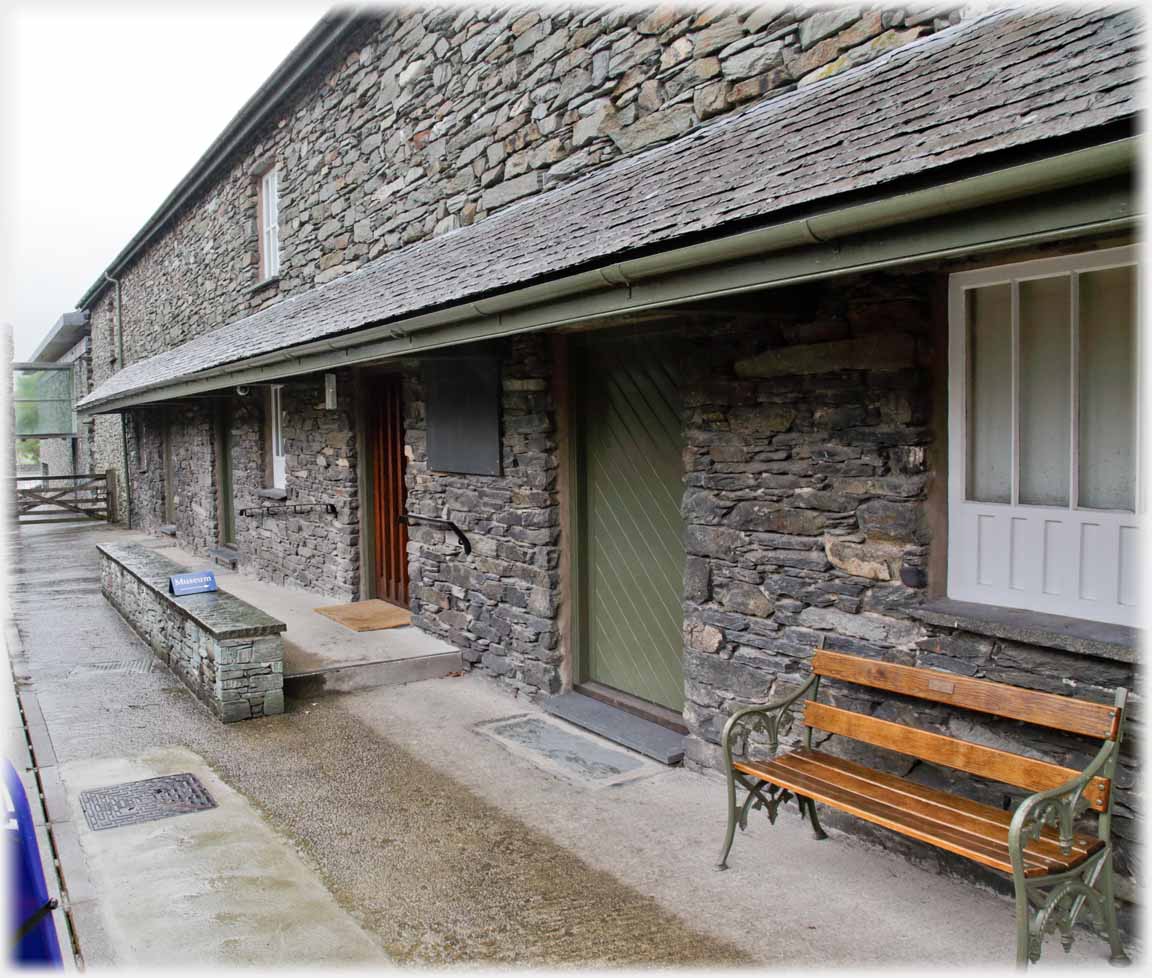 Front of building in dark stone with bench.