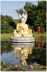 Gold statue in pool with snake, monk and water lilly.