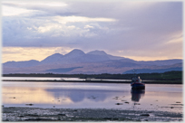 Beached boat with sea and mountains beyond.