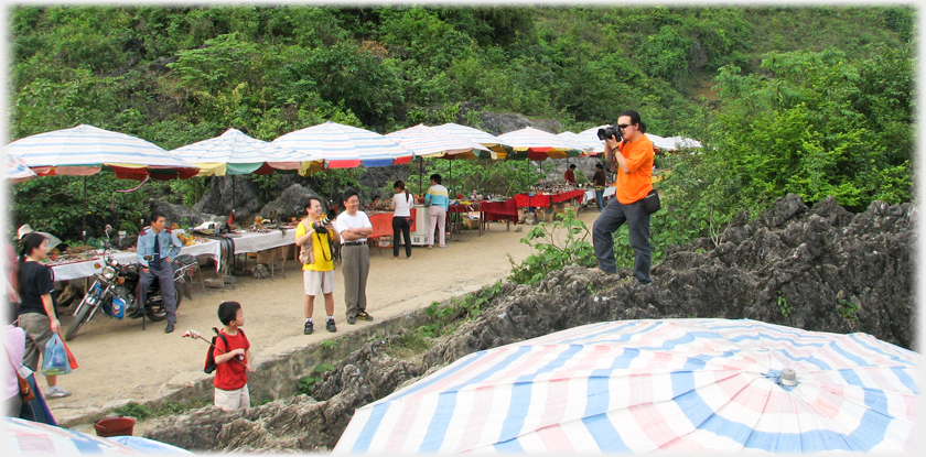 Chinese photographer taking pictures of the Vietnamese side of the market watched by policeman.