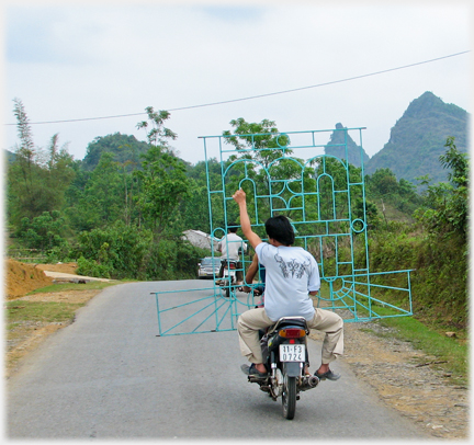 Pillion holding large grill, car coming.