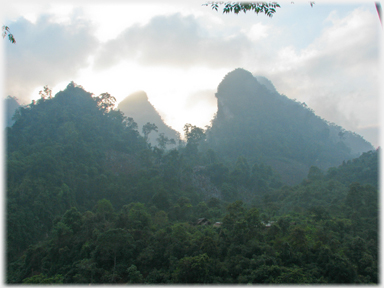 Sun rising behind a pointed karst.