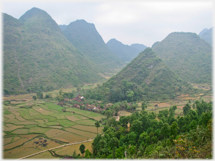 Scrub covered Karst with village and fields at its base.
